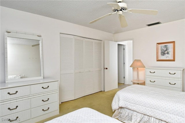 carpeted bedroom featuring ceiling fan, a textured ceiling, and a closet