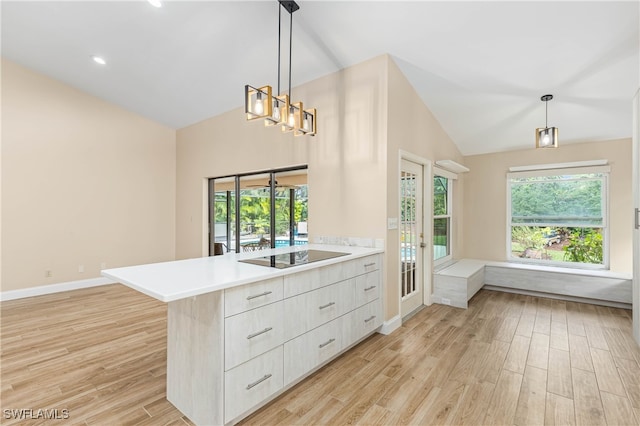 kitchen with pendant lighting, lofted ceiling, light wood-type flooring, black electric cooktop, and kitchen peninsula