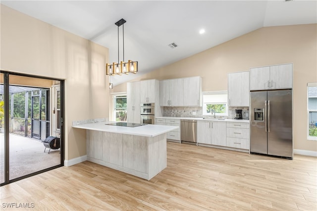 kitchen featuring sink, stainless steel appliances, backsplash, kitchen peninsula, and pendant lighting