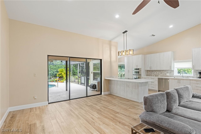 kitchen featuring lofted ceiling, white cabinets, appliances with stainless steel finishes, tasteful backsplash, and kitchen peninsula