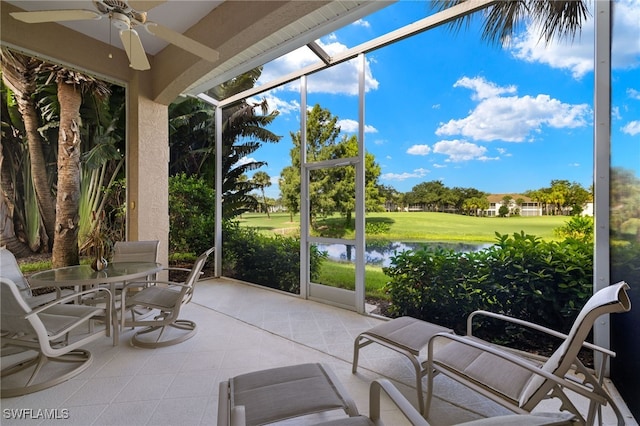 sunroom featuring ceiling fan and a water view