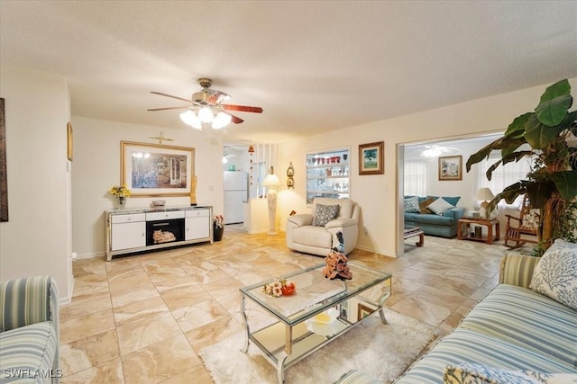 living room with ceiling fan and a textured ceiling