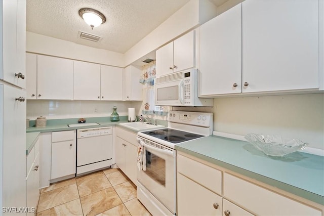 kitchen with white appliances, sink, a textured ceiling, light tile patterned flooring, and white cabinetry