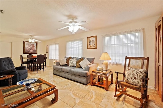 living room with a textured ceiling and ceiling fan