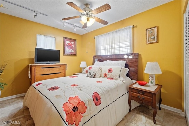 tiled bedroom with a textured ceiling, track lighting, and ceiling fan