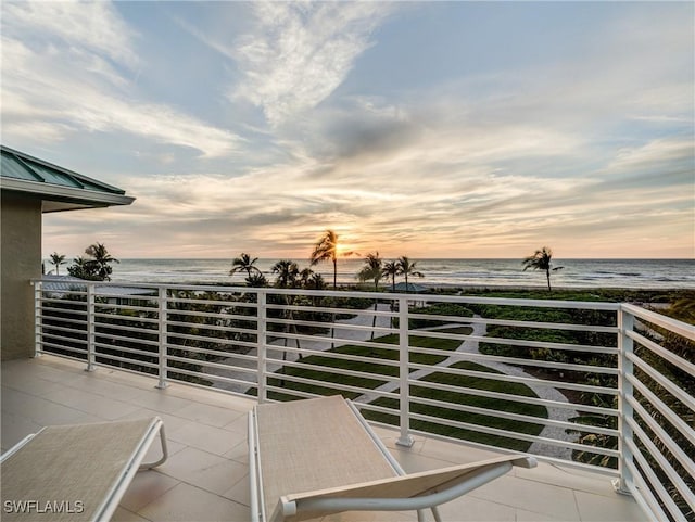 balcony at dusk featuring a water view