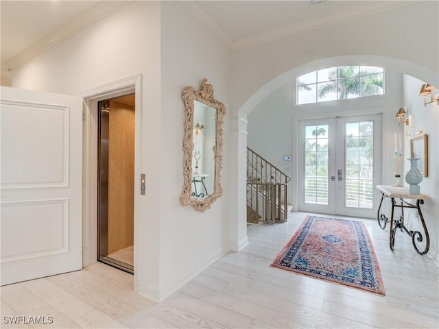 entrance foyer featuring arched walkways, wood finished floors, elevator, stairway, and french doors