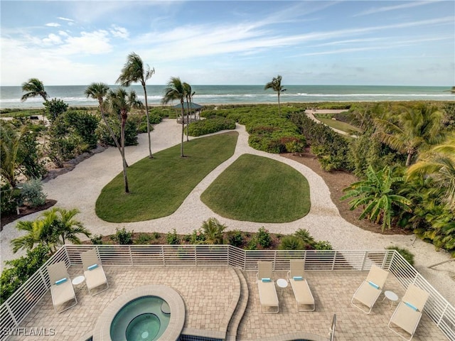 view of home's community with a water view, a lawn, and a jacuzzi