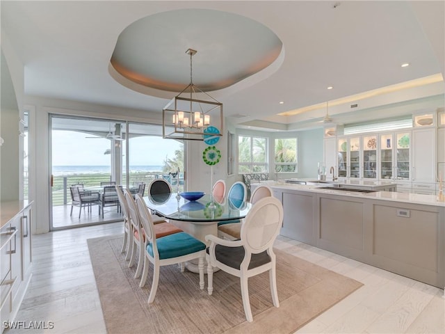 dining space featuring a raised ceiling, recessed lighting, and a notable chandelier