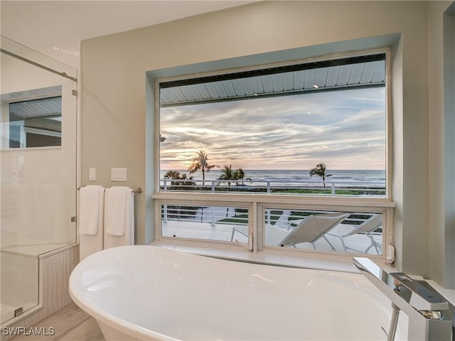 full bath featuring a freestanding bath and a water view