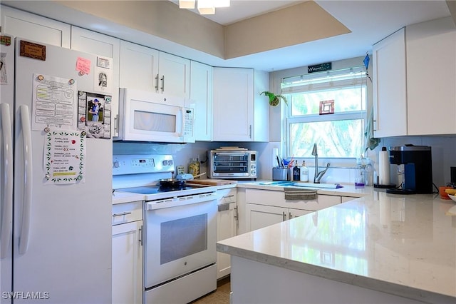 kitchen featuring white cabinetry, sink, light stone counters, and white appliances