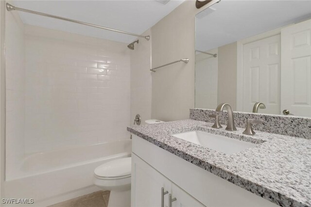 full bathroom featuring vanity, tiled shower / bath, tile patterned floors, and toilet