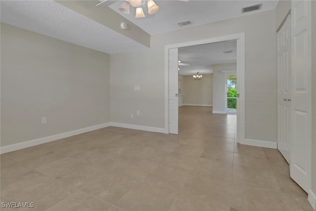 empty room with ceiling fan with notable chandelier