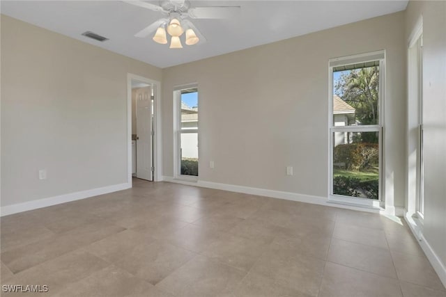 spare room with ceiling fan, light tile patterned floors, and a wealth of natural light