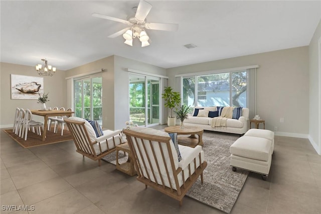 tiled living room with plenty of natural light and ceiling fan with notable chandelier