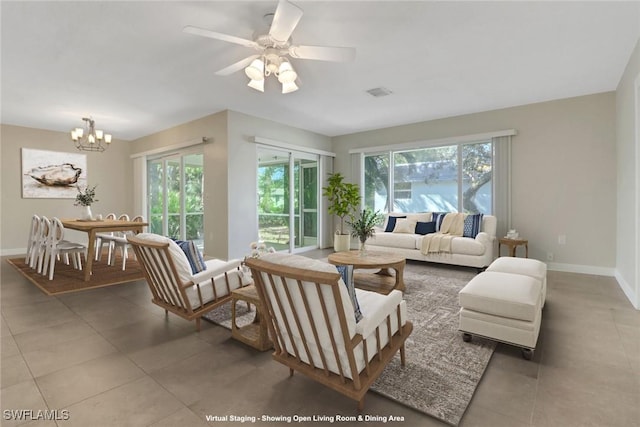 tiled living room featuring a healthy amount of sunlight and ceiling fan with notable chandelier