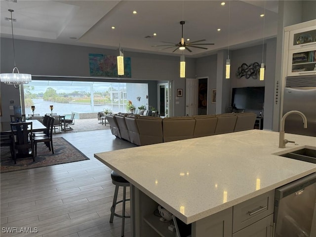 kitchen featuring ceiling fan with notable chandelier, a water view, hanging light fixtures, light stone countertops, and appliances with stainless steel finishes