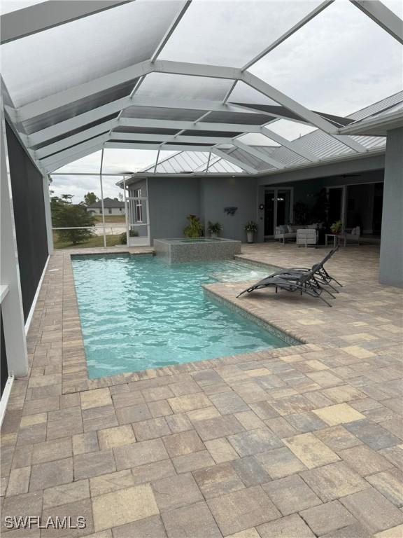 view of pool with pool water feature, glass enclosure, and a patio area