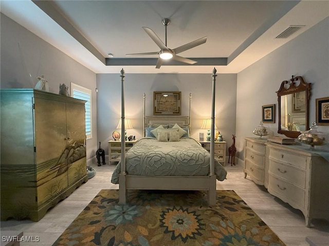 bedroom featuring a tray ceiling, ceiling fan, and light hardwood / wood-style flooring