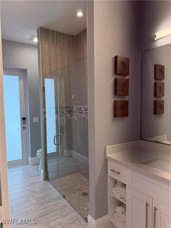 bathroom with vanity, a shower with shower door, and toilet