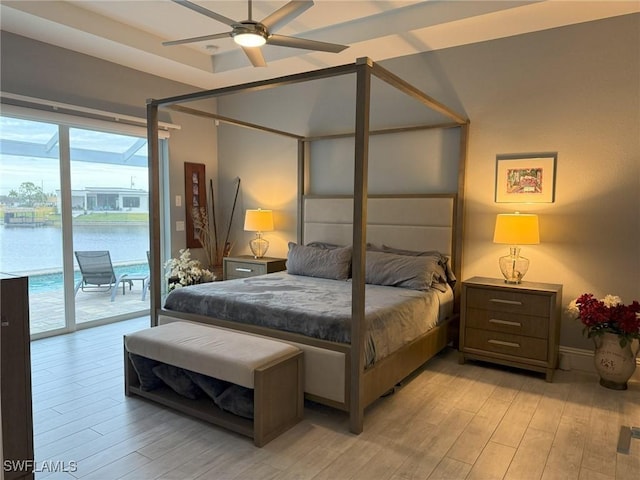 bedroom featuring access to outside, light wood-type flooring, a water view, and ceiling fan