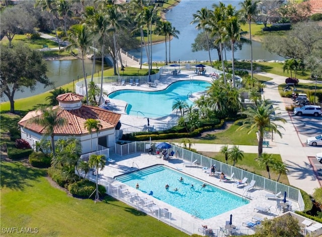 view of swimming pool featuring a water view, a patio area, and a lawn