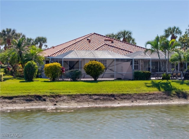 back of house with a water view, a lanai, and a lawn