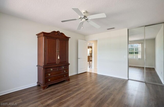 unfurnished bedroom featuring dark hardwood / wood-style floors, a textured ceiling, ceiling fan, and a closet