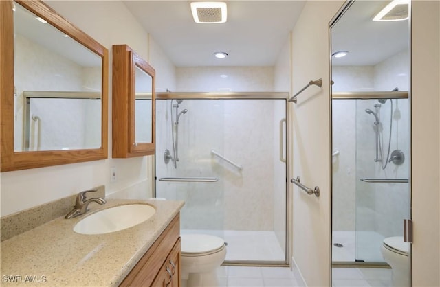 bathroom with vanity, a shower with shower door, tile patterned floors, and toilet