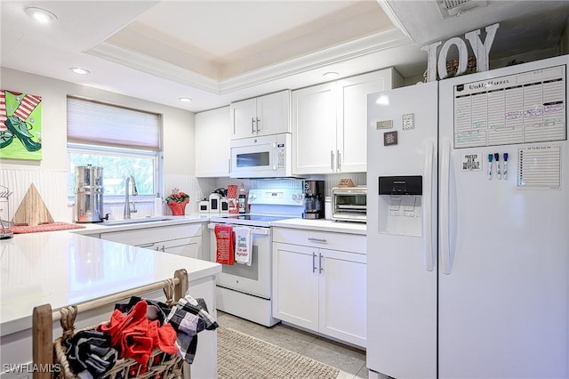 kitchen featuring white cabinetry, sink, white appliances, a tray ceiling, and ornamental molding