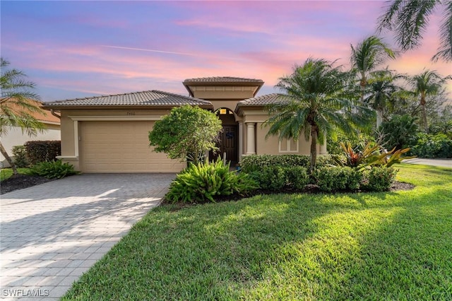 mediterranean / spanish-style house featuring a garage and a lawn