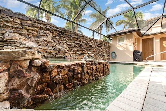 view of pool featuring a patio, pool water feature, and glass enclosure