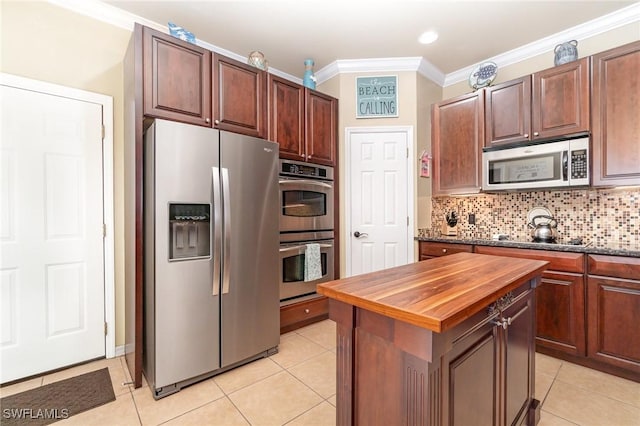 kitchen with wood counters, crown molding, light tile patterned floors, appliances with stainless steel finishes, and backsplash