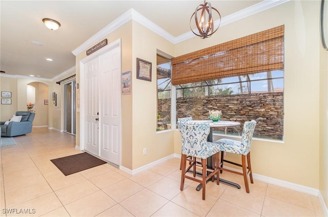 tiled dining space featuring ornamental molding and a chandelier