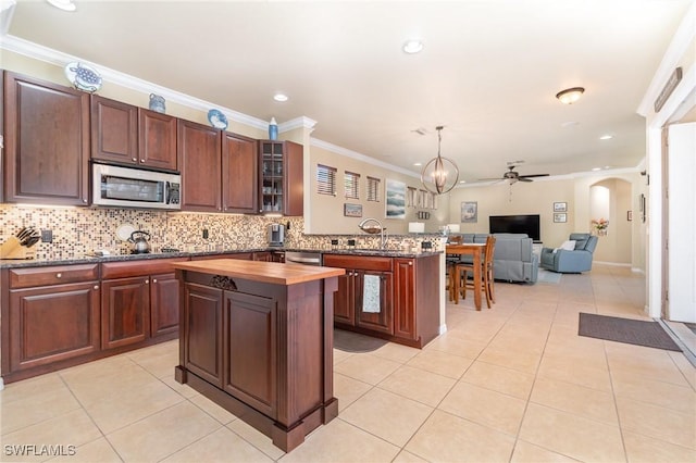 kitchen with ceiling fan with notable chandelier, hanging light fixtures, ornamental molding, light tile patterned floors, and stainless steel appliances