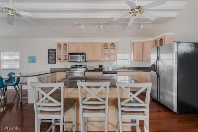 kitchen featuring appliances with stainless steel finishes, dark hardwood / wood-style flooring, a breakfast bar, ceiling fan, and sink