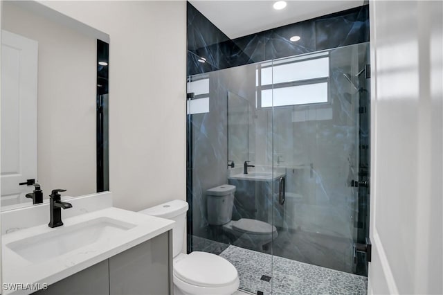 bathroom featuring vanity, toilet, and a shower with door