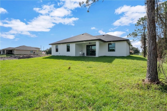 rear view of property with ceiling fan and a yard