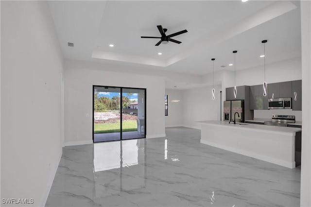 kitchen with ceiling fan, sink, decorative light fixtures, a tray ceiling, and appliances with stainless steel finishes