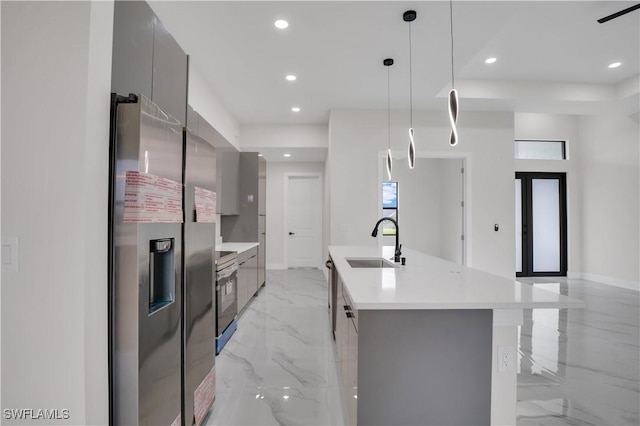 kitchen featuring pendant lighting, a kitchen island with sink, sink, gray cabinets, and appliances with stainless steel finishes