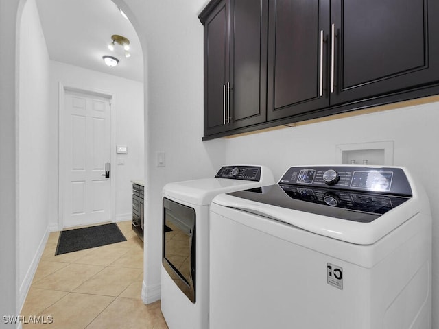 laundry room with light tile patterned floors, washing machine and dryer, baseboards, and cabinet space