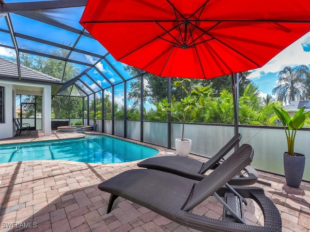 view of pool featuring glass enclosure, a fenced in pool, a patio, and an in ground hot tub