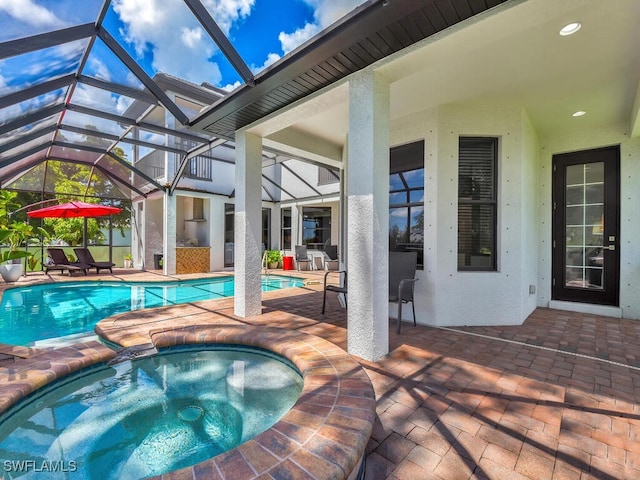 outdoor pool with glass enclosure, a patio, and an in ground hot tub