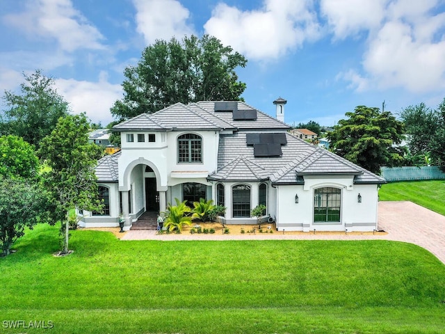 mediterranean / spanish-style home with a front yard, solar panels, a tile roof, and stucco siding