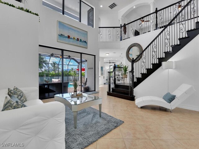 tiled living room with ceiling fan and a towering ceiling