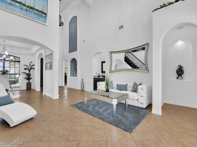 interior space with baseboards, arched walkways, tile patterned floors, stairs, and a chandelier