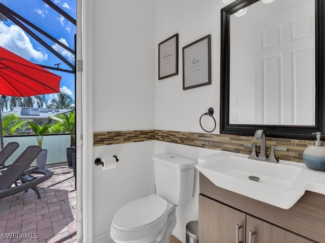 half bathroom with toilet, brick floor, and vanity