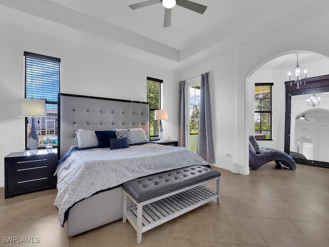 bedroom with tile patterned flooring, arched walkways, and ceiling fan with notable chandelier