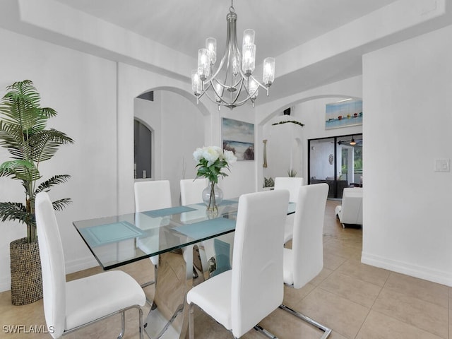 dining area featuring arched walkways, light tile patterned flooring, an inviting chandelier, and baseboards