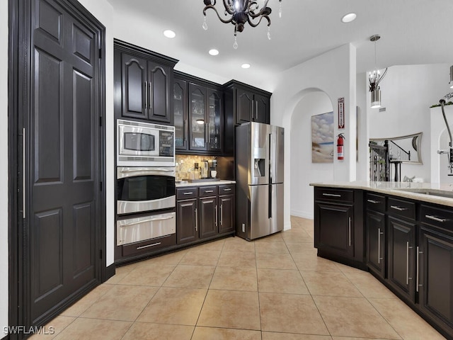 kitchen featuring a notable chandelier, a warming drawer, stainless steel appliances, light countertops, and light tile patterned flooring